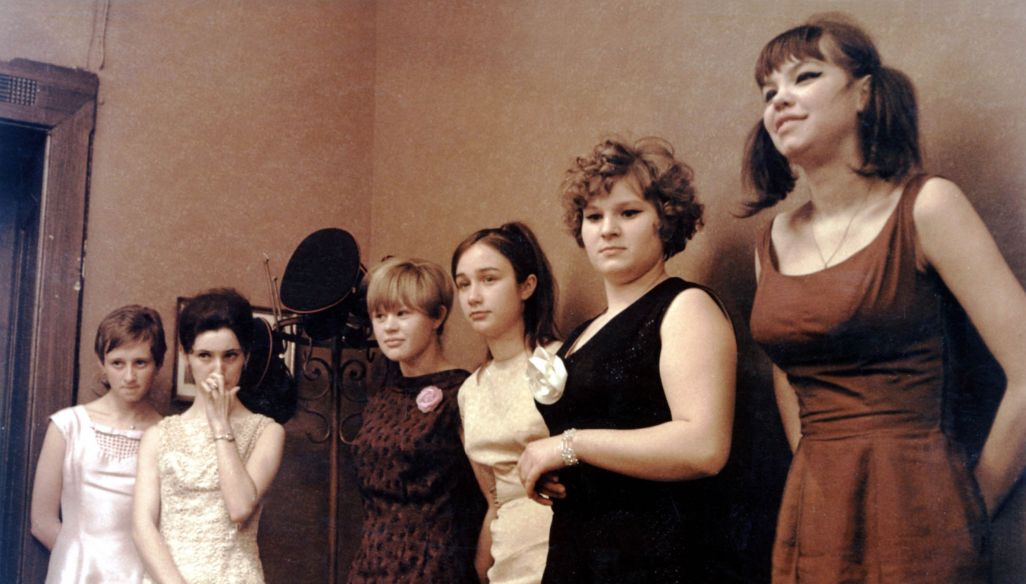 zdjęcie z filmu - fotos ukazujący 6 kobiet stojących pod ściana w biurze. 