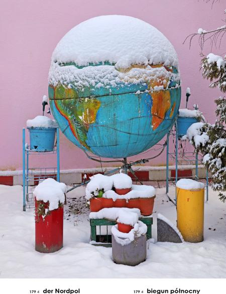 fotografia ukazująca globus ustawiony w mini ogródku, wokół chaotycznie rozstawione elementy  w różnych kolorach