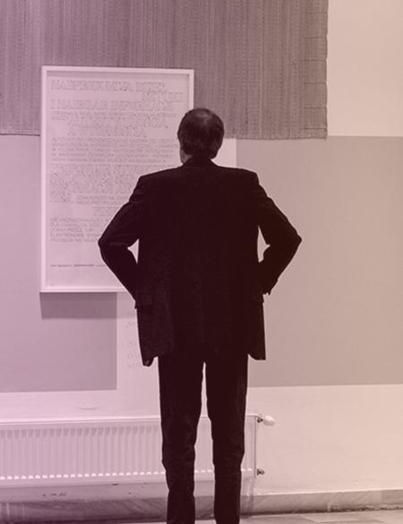 mężczyzna stoi przed pracami zawieszonymi na ścianie 