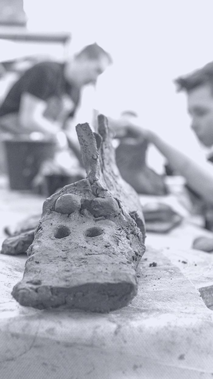 czarno białe zdjęcie ukazujące osoby pracujące w glinie, tworzą rzeźby